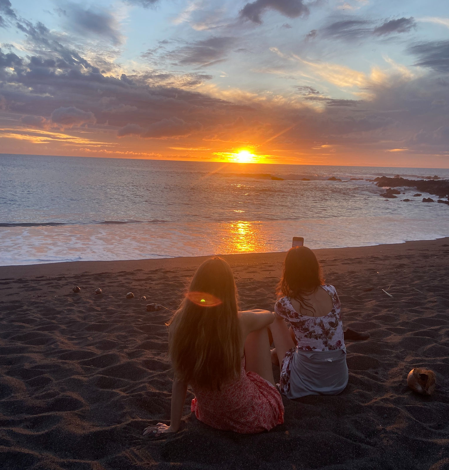 two woman watching the sunset on a beach